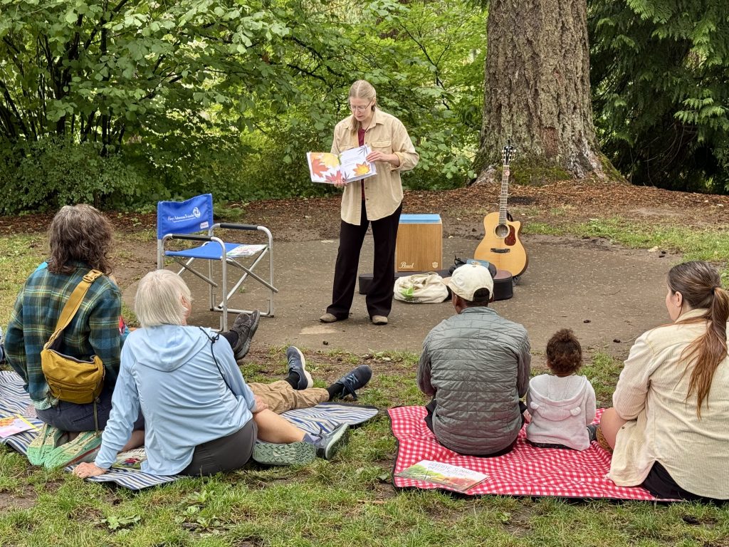 Audrey Sauble reading a book to a group at Hoyt Arboretum